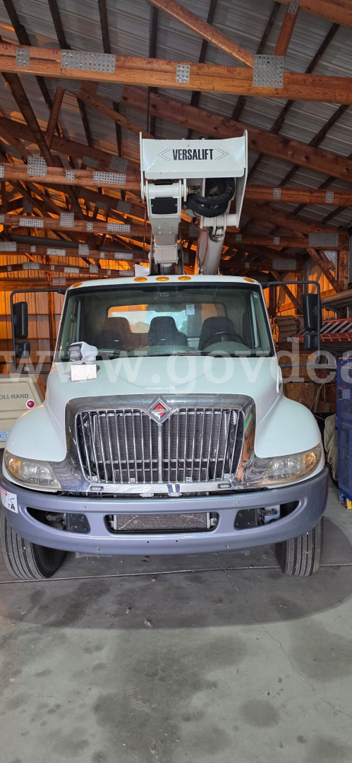 Front view of a 2016 International 4300 truck with a Versalift boom in a warehouse; grille, headlights, and bumper visible.