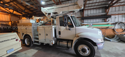 International 4300 boom truck in a service bay showing crane outrigger, utility compartments, and cab with stock number plate 25948-6.