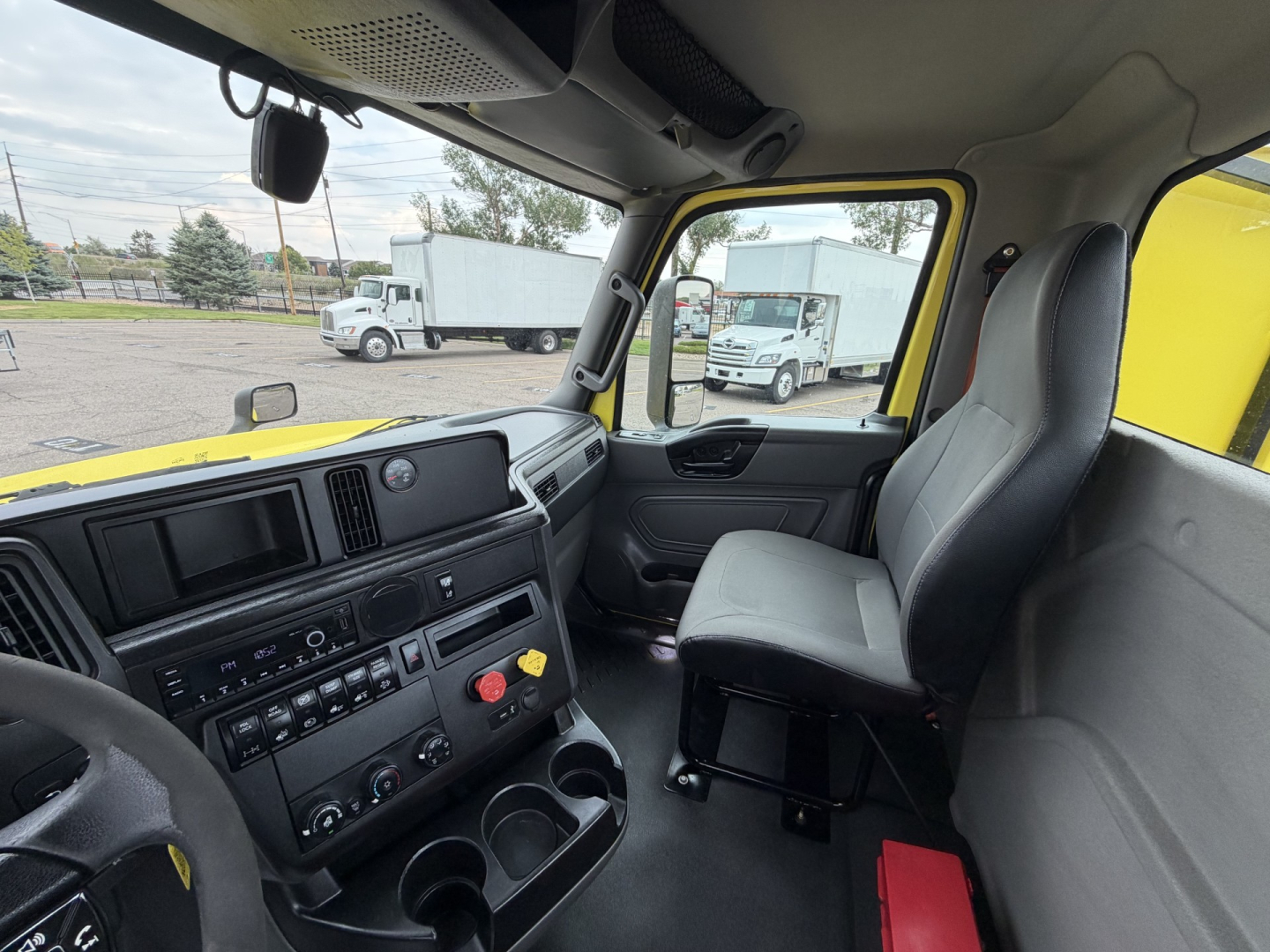 Interior view of a 2023 International LT625 truck cab showing dashboard controls, steering wheel, and passenger seat with driver seat on right side.
