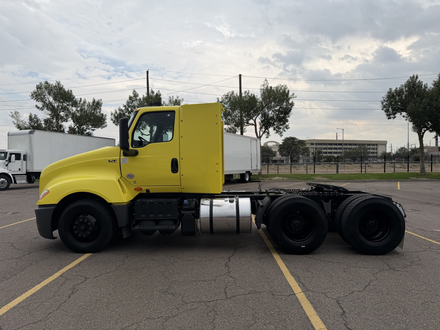 Truck side view showing yellow cab and chassis of a 2023 International LT625 with dual rear axles and fuel tank visible