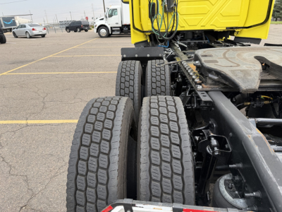 Two large dual rear tires on a truck chassis with yellow cab visible in background