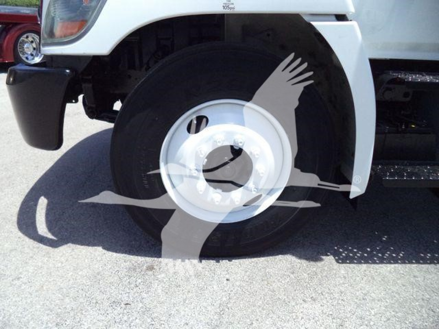 Front wheel and fender of a white 2020 Hino 268A box truck showing front tire and wheel well.
