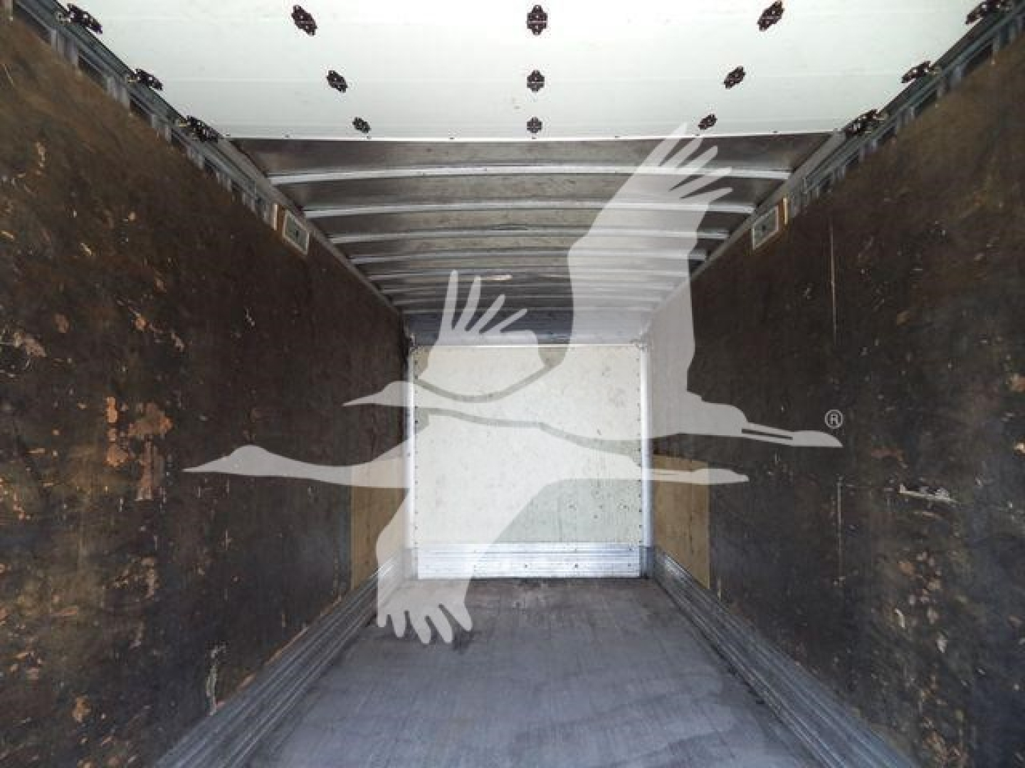 Truck cargo area interior showing metal overhead rails and wooden sides with signs of wear.