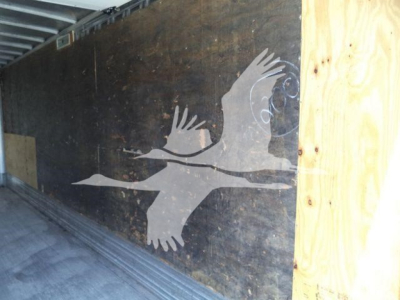 Truck trailer interior with a mural of flying birds on a dark wall and wooden framing.