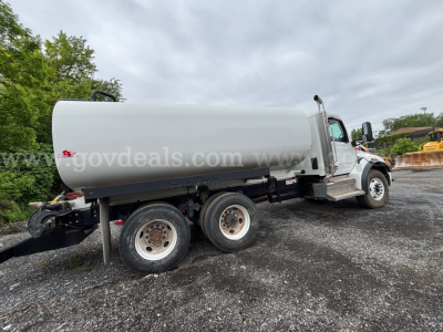 Dump truck with large cylindrical tank mounted on a chassis showing rear wheels and cab, side view, 2009 International 7400.