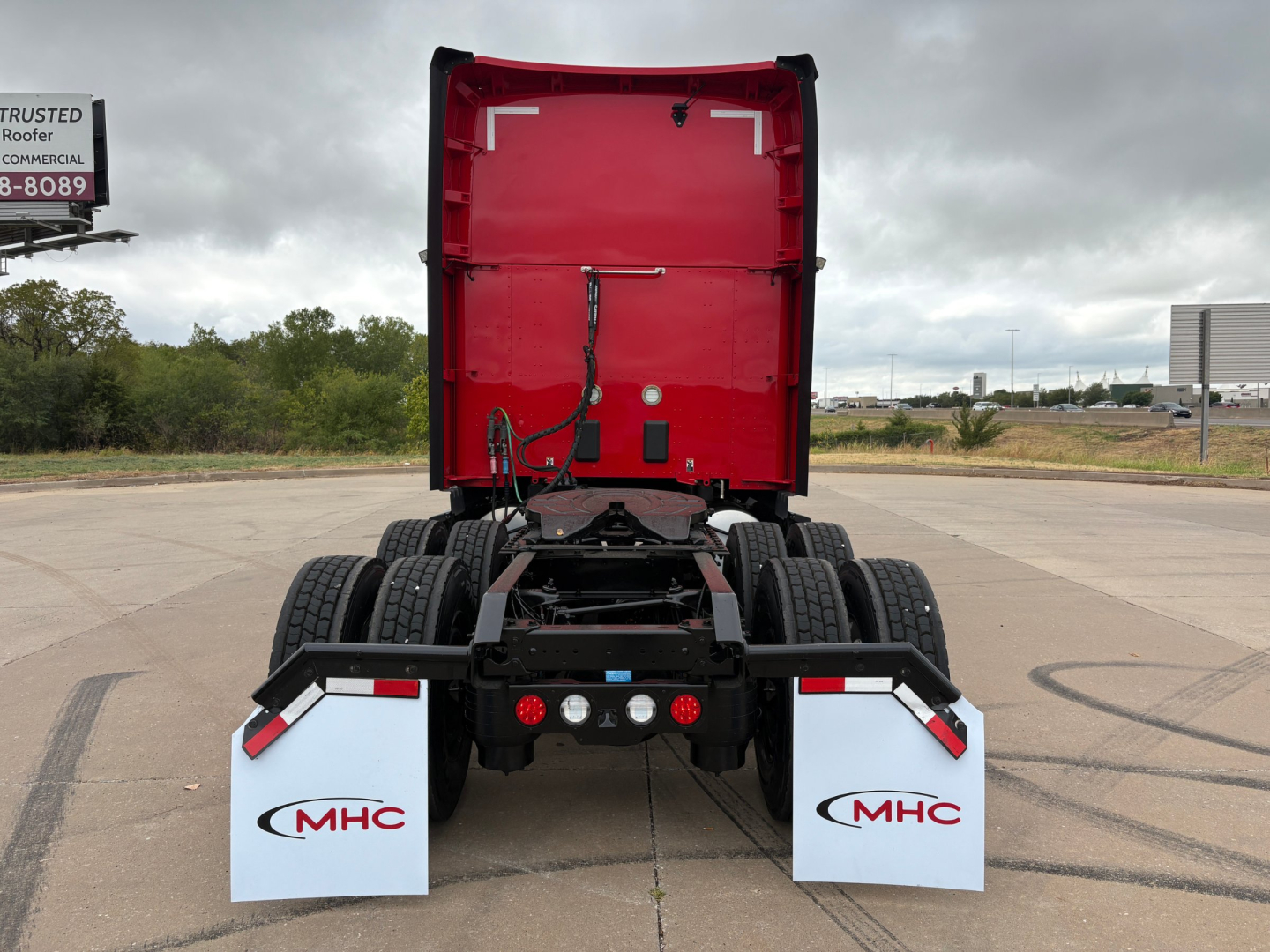 Kenworth T680 wheelbase tractor rear view showing mud flaps with MHC logos and fifth wheel area.