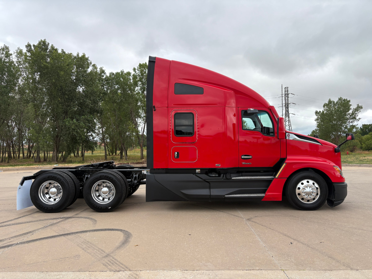 Kenworth T680 tractor trailer in red, side view showing cab and rear wheels.