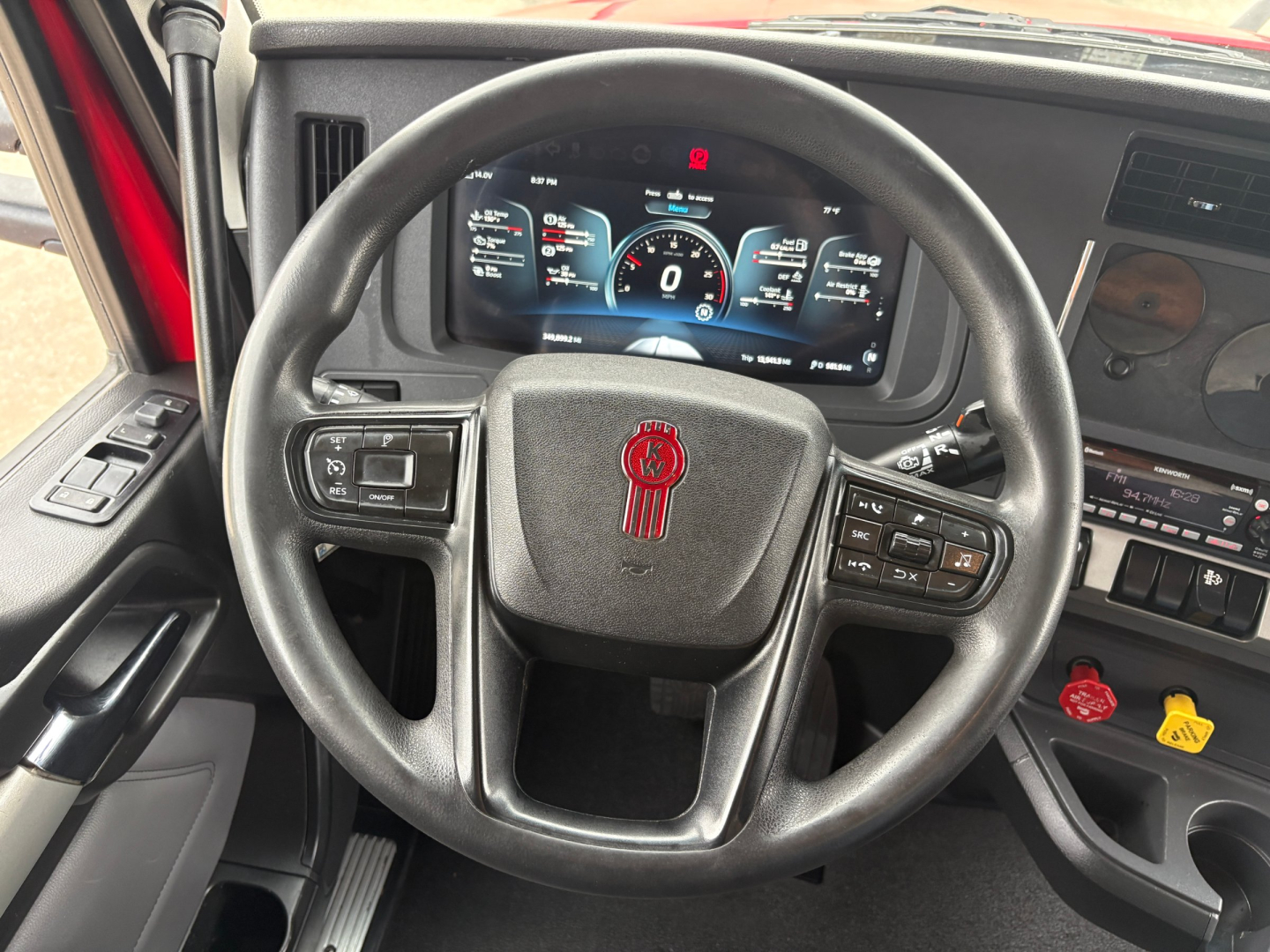 Kenworth T680 steering wheel and dashboard view in cab showing digital instrument cluster and controls.