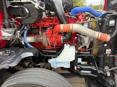 Kenworth T680 engine bay showing red engine, turbocharger, blue hoses, and radiator components.