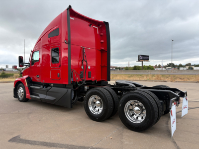 Kenworth T680 truck side view showing red sleeper cab and dual rear axles with chrome wheels.