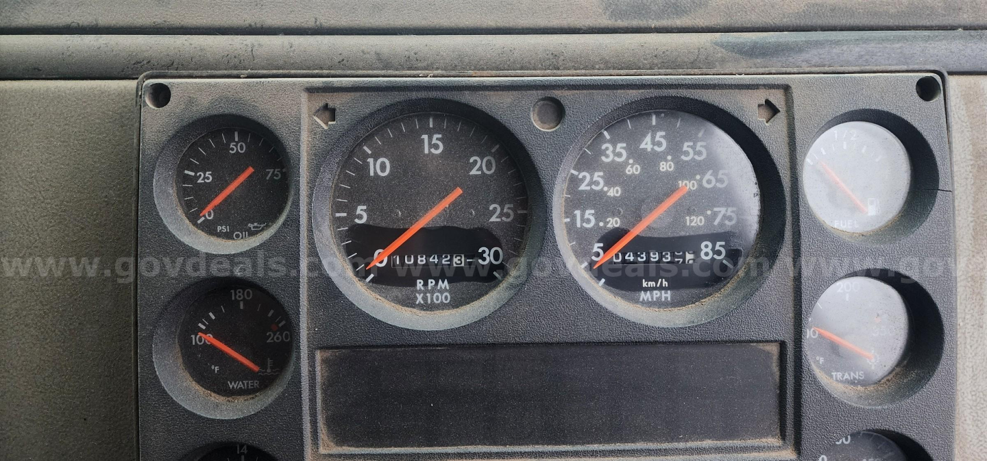 Dashboard gauges showing speedometer, tachometer, and fuel/engine indicators in a Freightliner FL70 cab; visible numbers include RPM x1000, MPH, and gauge needles.