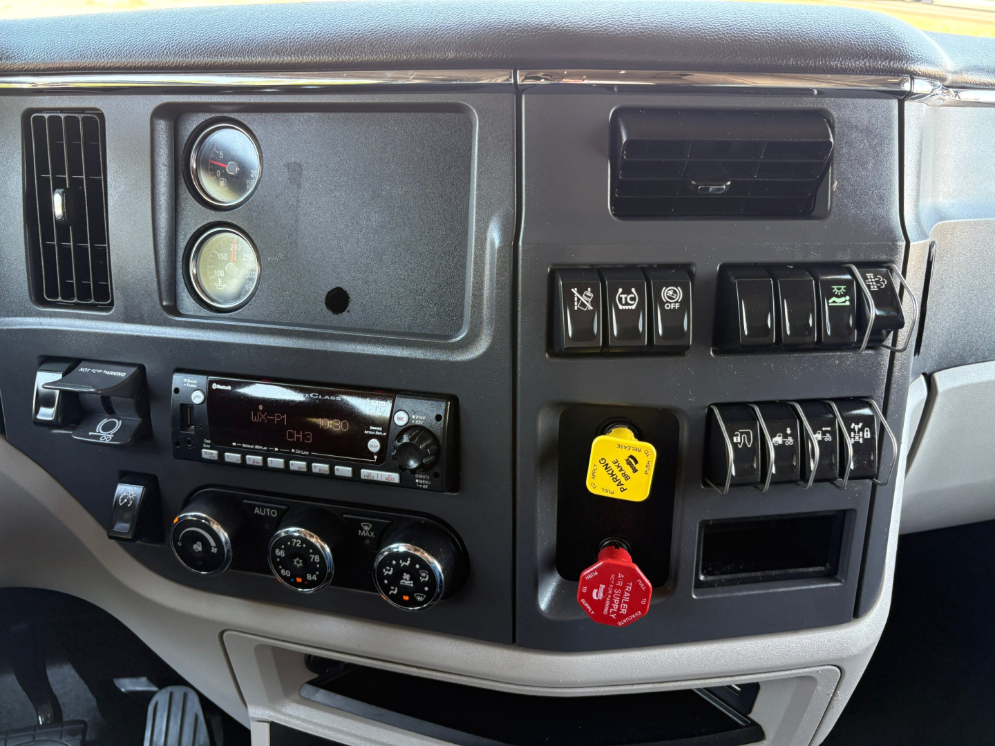 Peterbilt 579 dash area showing gauges and controls, with yellow and red warning/power knobs and climate controls.