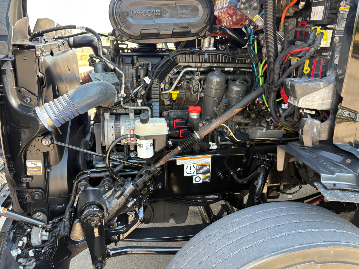 Peterbilt 579 engine bay showing top view with air intake, hoses, and electrical harnesses visible.