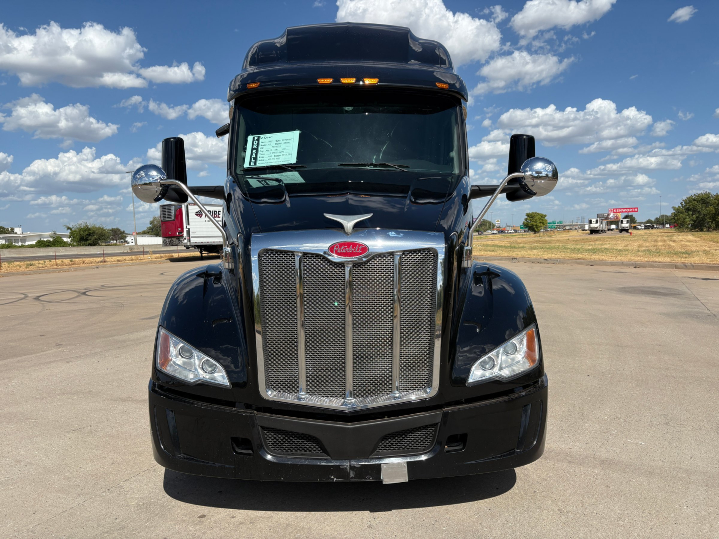 Peterbilt 579 front view showing chrome grille, headlights, and badge in a parking lot under blue sky.