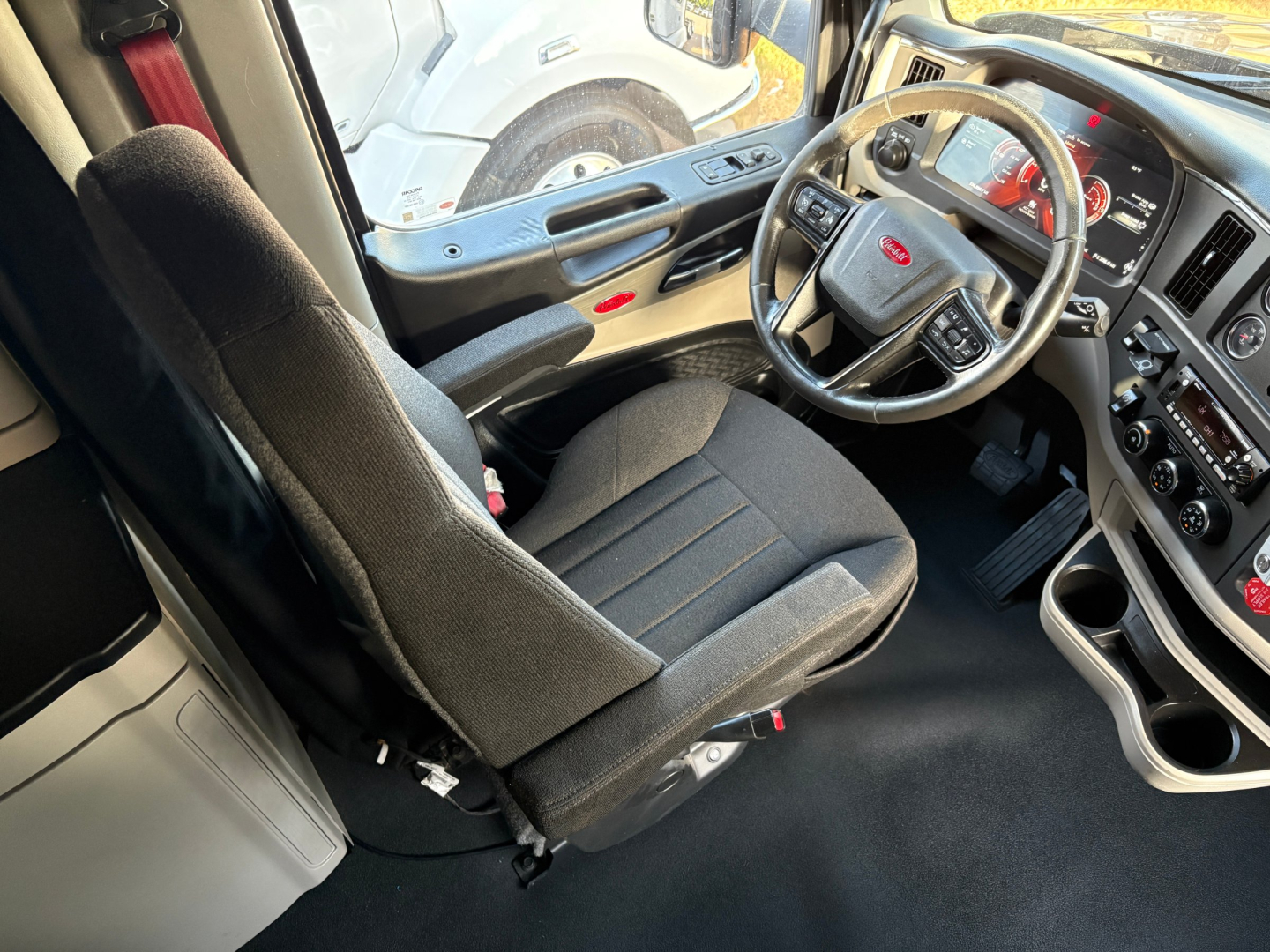 Peterbilt 579 truck interior driver's seat and steering wheel viewing from passenger side with dashboard and controls visible.