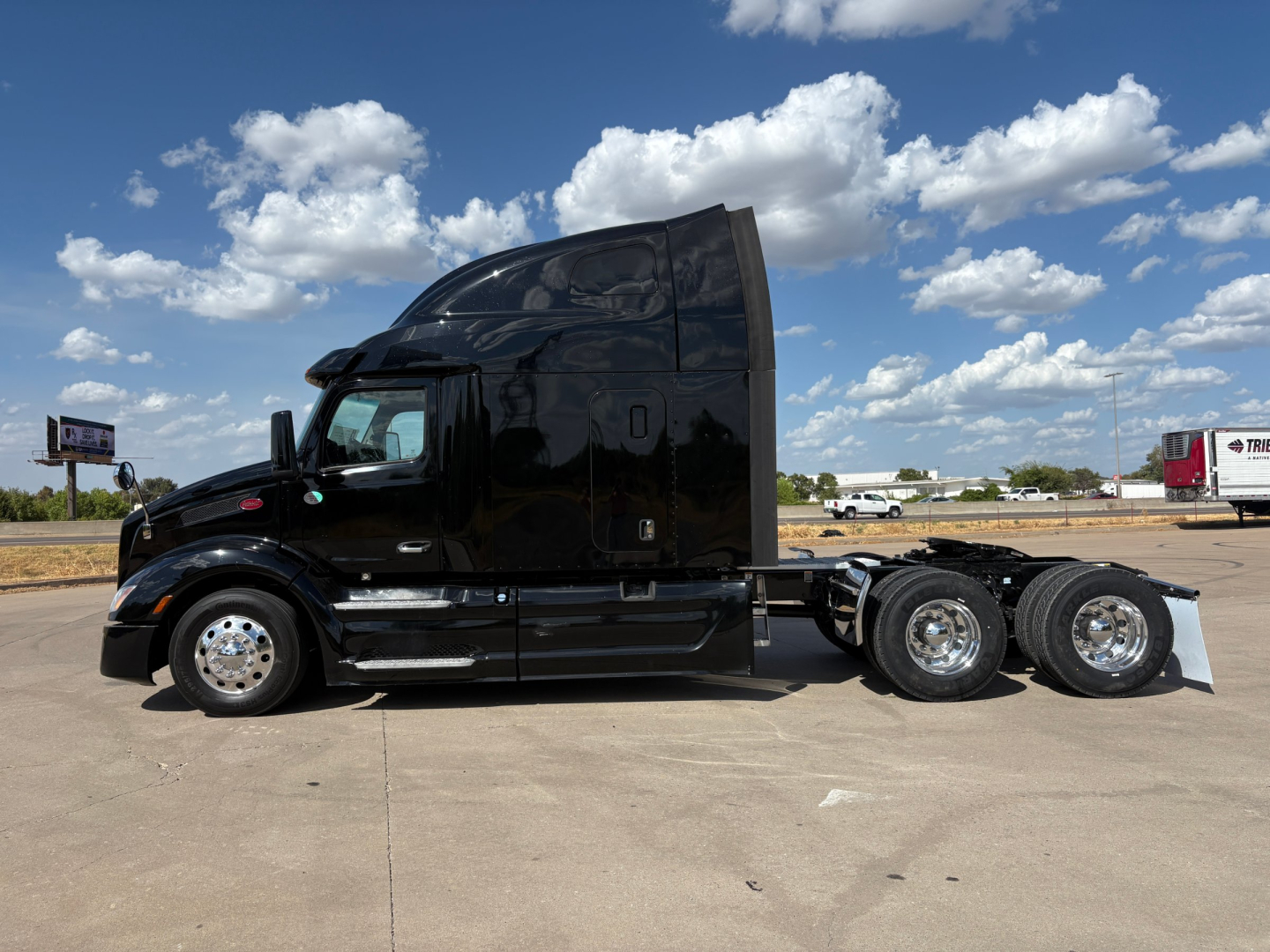 Peterbilt 579 conventional sleeper truck in black, side view showing cab, rear dual axles, chrome wheels, and fuel tanks.