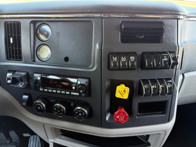 Peterbilt 579 dash area showing gauges and controls, with yellow and red warning/power knobs and climate controls.