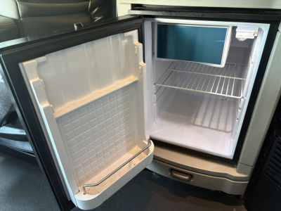 Refrigerator in a Peterbilt 579 cab showing empty fridge with shelves and door storage.