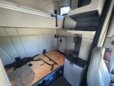  Peterbilt 579 sleeper cab interior with side storage console and exposed wooden sleeper platform, dash area visible.