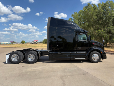 Peterbilt 579 truck tractor side view showing sleeper cab and dual rear axles in a parking lot.
