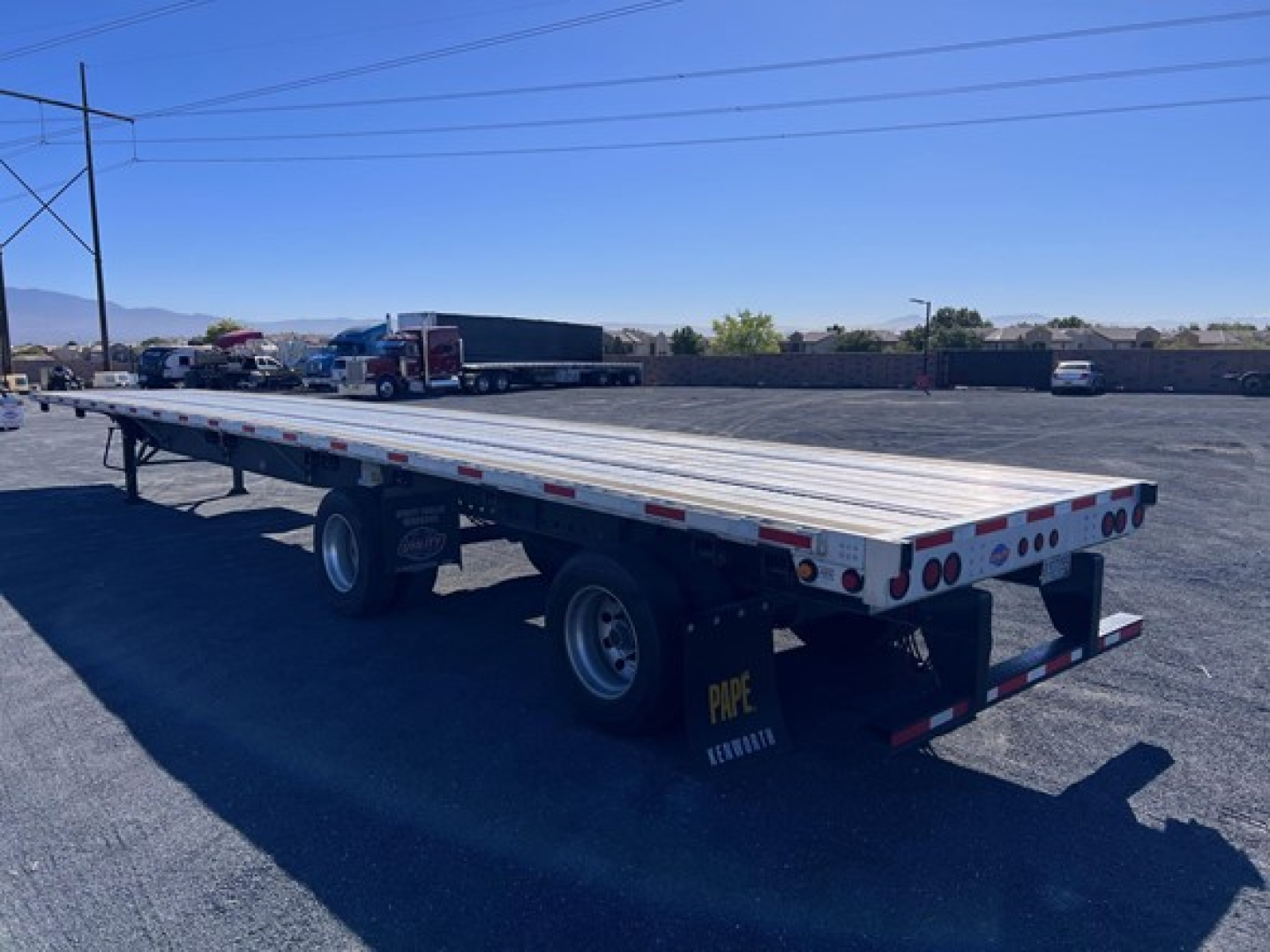 Flatbed trailer showing long aluminum deck with dual tandem axles and rear bumper, Utility 4000Ae model in a parking lot.