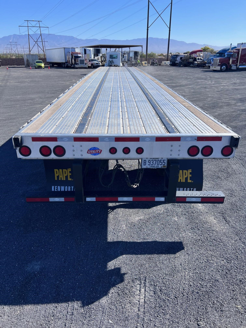 Flatbed trailer deck with Utility 4000AE branding and rear lights; long aluminum entries, bumper with reflective tape, license plate area, and PAPE Kenworth branding.