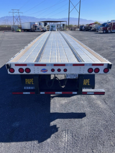 Flatbed trailer at rear showing aluminum deck and taillights with PAPE and Kenworth branding.