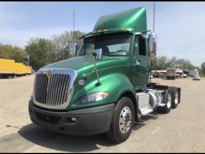 Cab and chassis showing a green 2017 International ProStar+ truck with a stacked exhaust and dual rear axles, daytime outdoor lot.