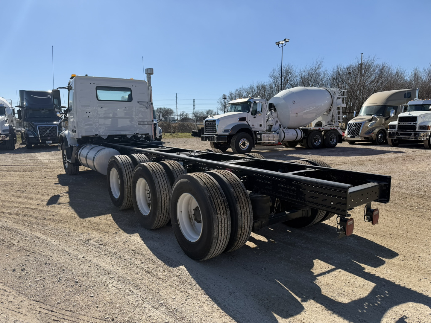 Volvo VHD86B300 cab and chassis truck chassis rear view showing three axles and dual rear tires.