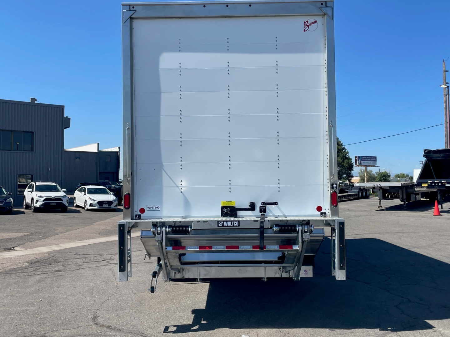 Rear view of a 2025 Mack MD6 box truck showing back doors and trailer hitch with reflective tape.