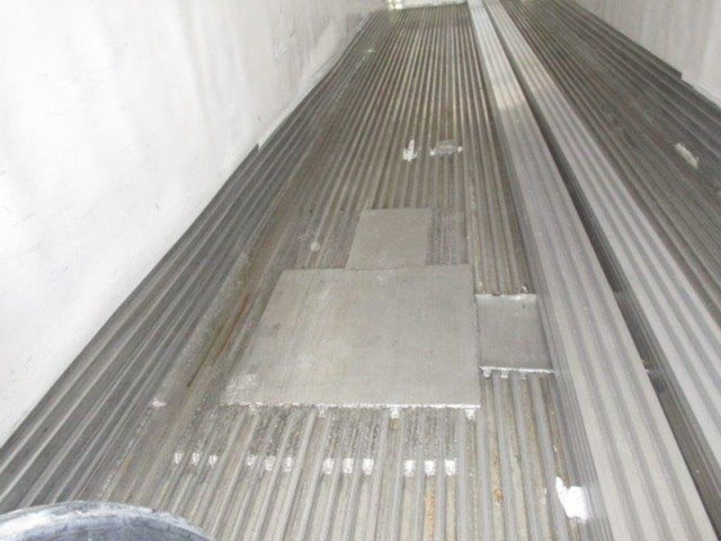Trailer interior with ribbed floor and metal access panels, cargo area of a refrigerated trailer.