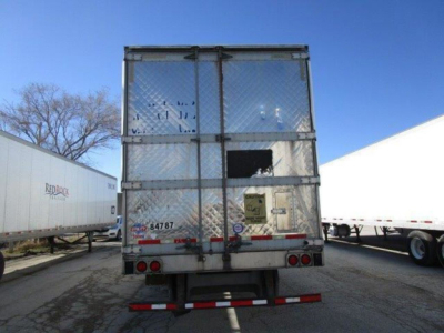 Refrigerated trailer rear showing metal mesh doors, two red/amber taillights, bumper, and a yellow warning placard; visible text includes stock number and decals on doors and bumper area.