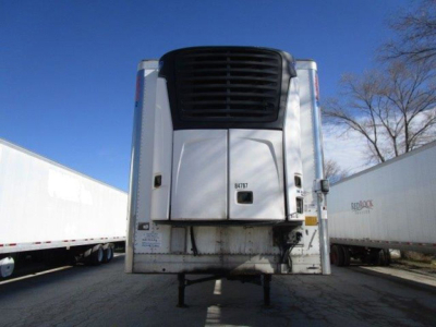 Rear view of a refrigerated trailer with a Thermo King or similar unit on front; no visible text legible on the unit in this view; metal rear with black intake grating; trailer legs and hitch area visible.