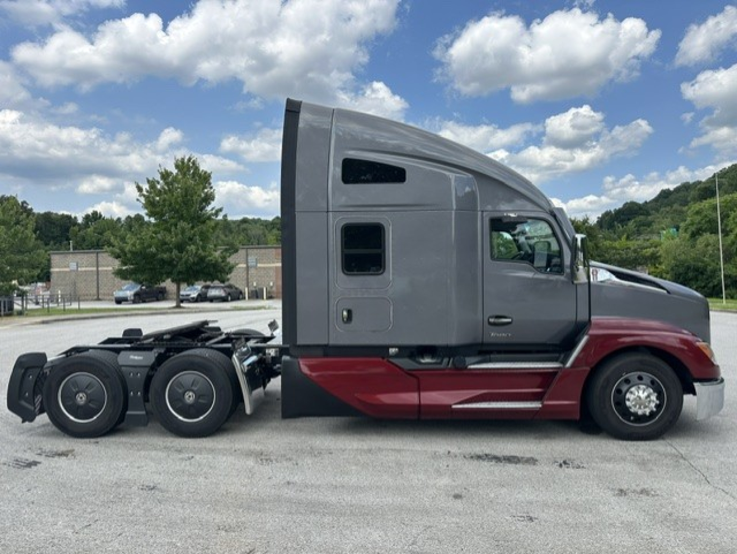 Kenworth T680 conventional sleeper truck in gray and red, side view showing cab and rear axles with tandem wheels.