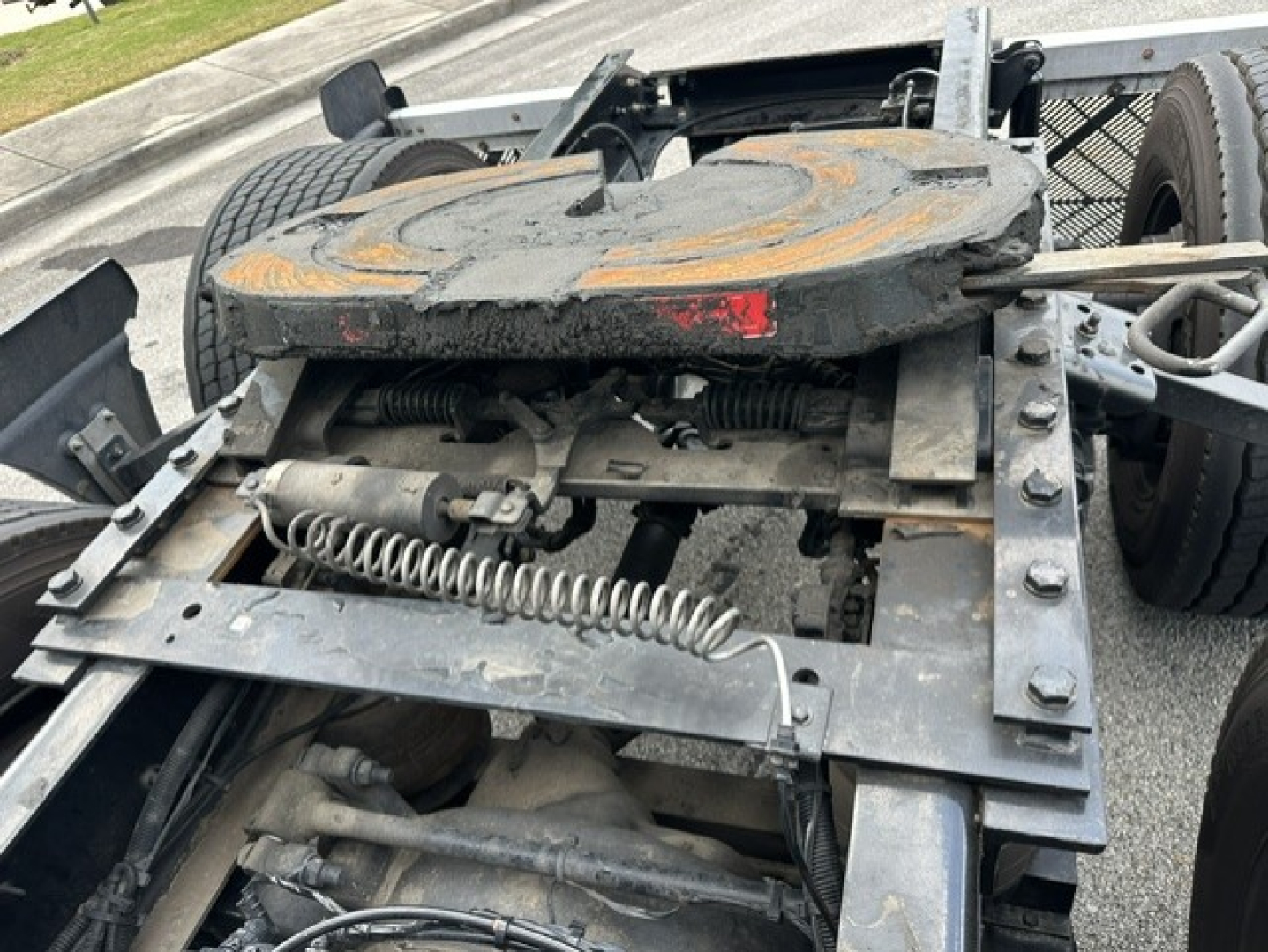 Trunnion and fifth wheel area of a Kenworth T680 tractor showing mounting frame, air springs, and hydraulic lines.