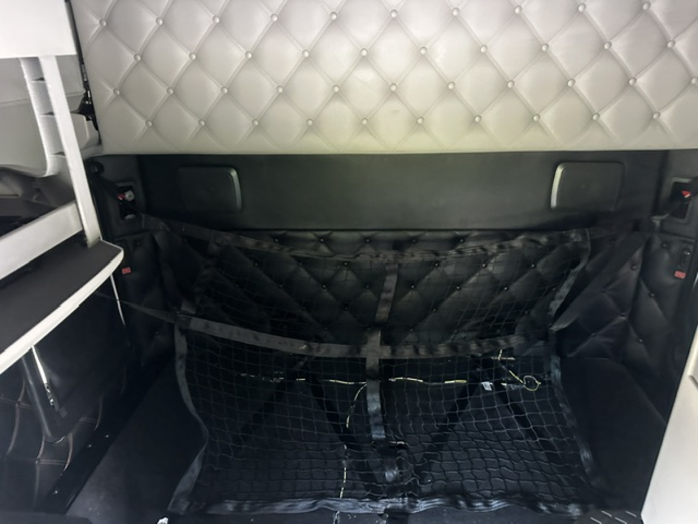 Kenworth T680 sleeper cab interior showing cargo area with quilted upholstery and a black cargo net.
