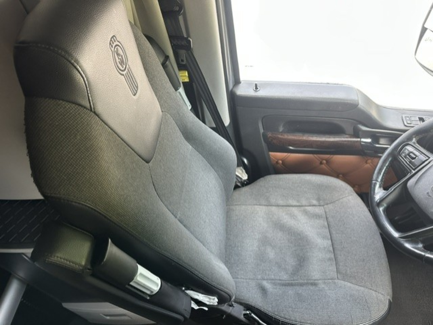 Kenworth T680 truck interior seat and steering wheel view showing fabric seat and door panel