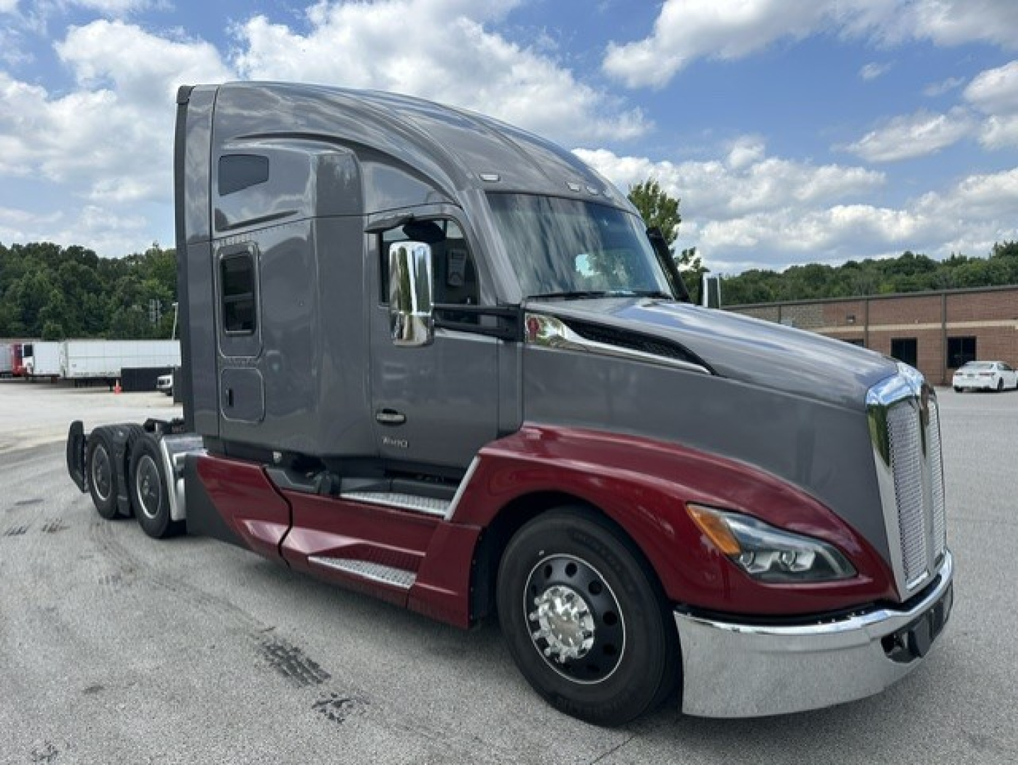 Kenworth T680 sleeper cab truck in gray and maroon, side view showing cab and front chrome bumper.