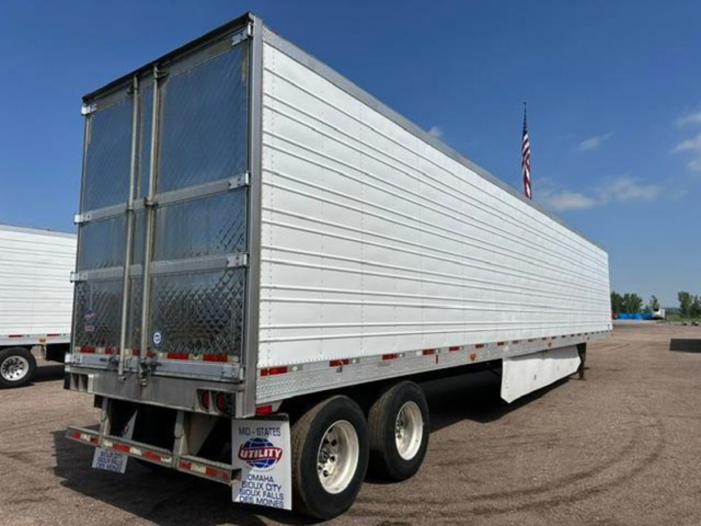 Utility reefer trailer in side view showing aluminum box with tandem rear axles and swing doors.