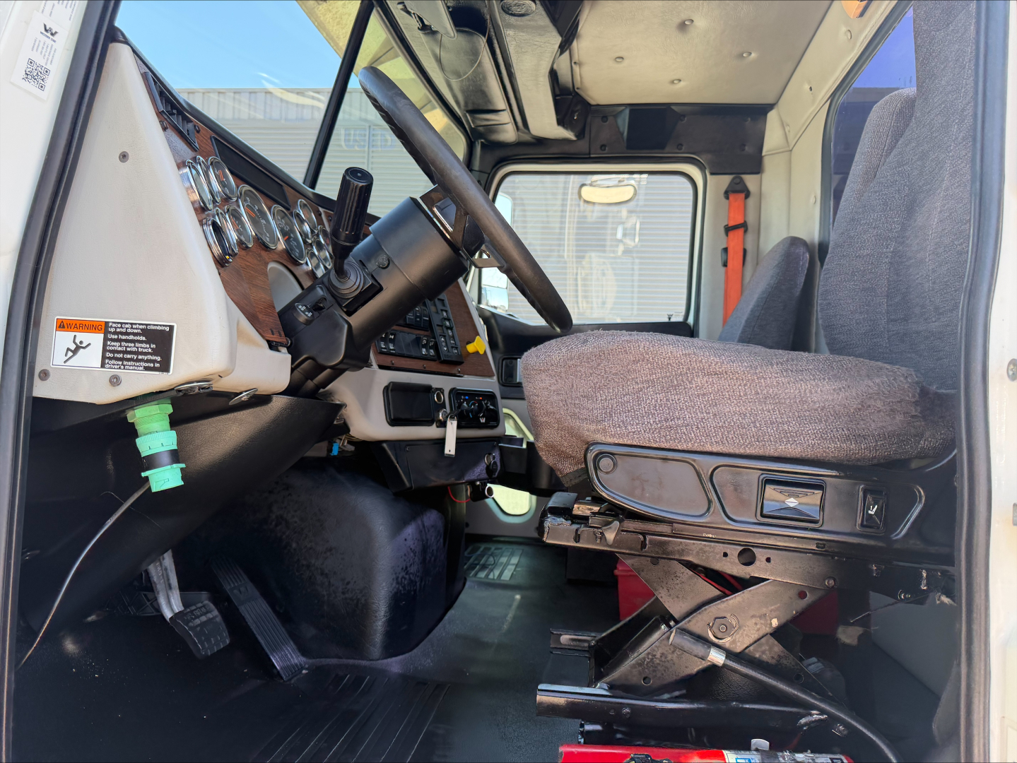 Interior of a 2017 Western Star 4700SF truck cab showing steering wheel, dashboard with gauges, driver’s seat, and entry area.