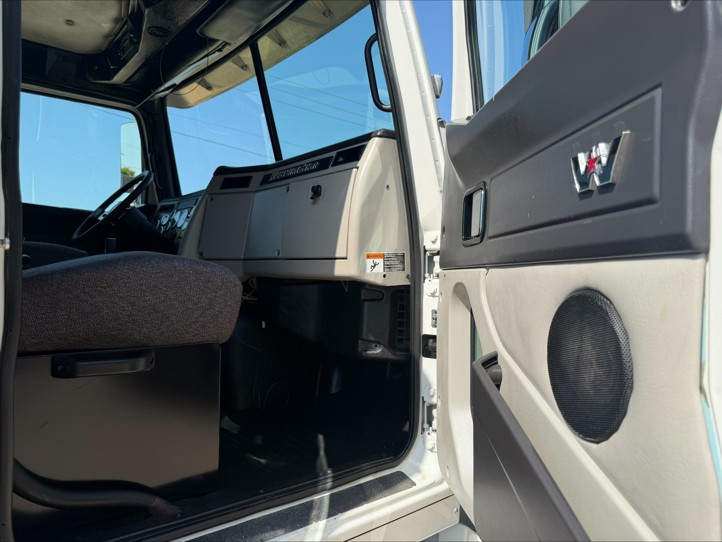 Truck cab interior of a 2017 Western Star 4700SF with open driver door showing dashboard, steering wheel, and seat.