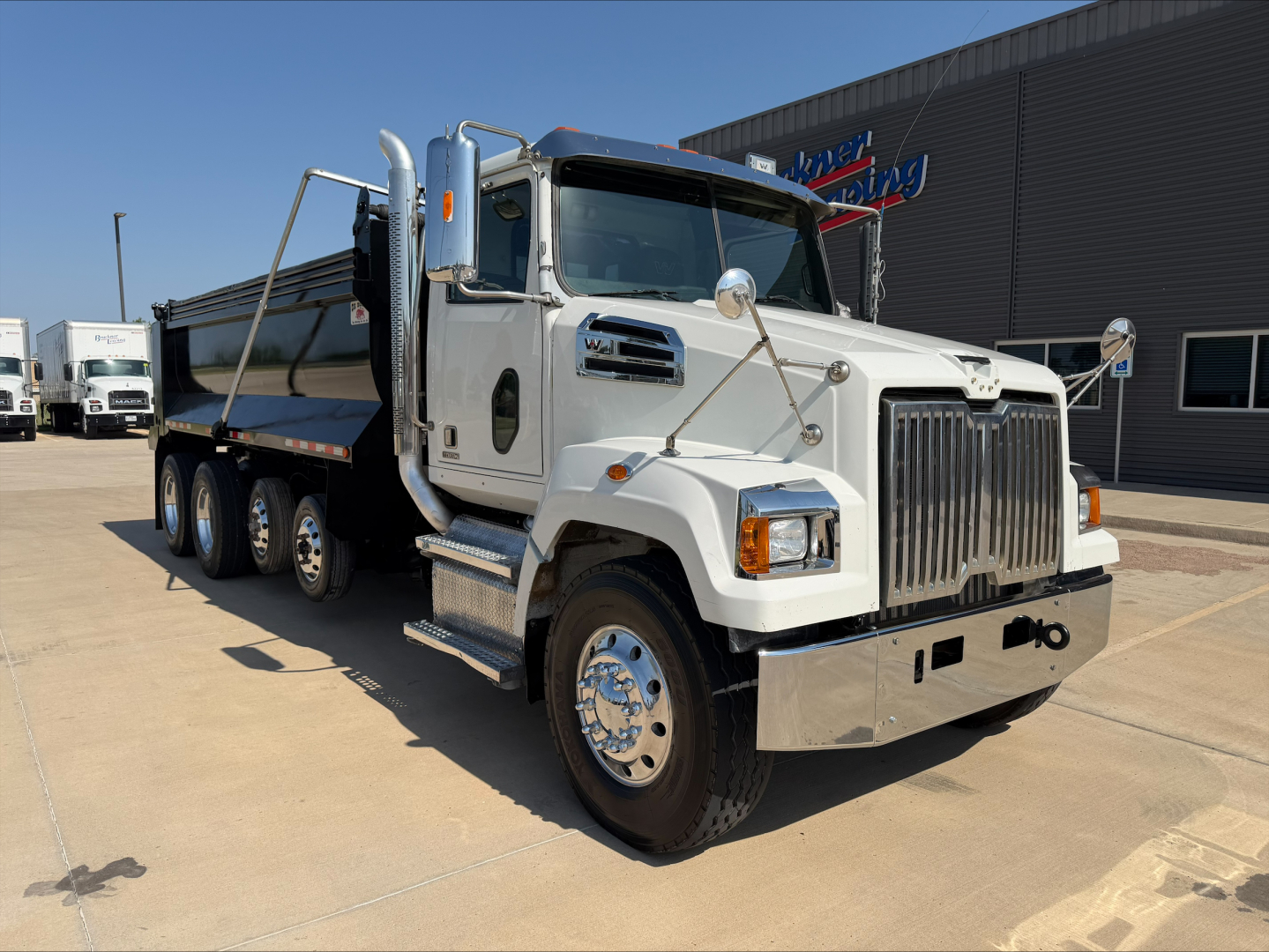 Truck: white Western Star 4700SF dump truck with chrome grille and multiple axles. Visible text includes Western Star logo on grille and side, no text legible on signage beyond brand.