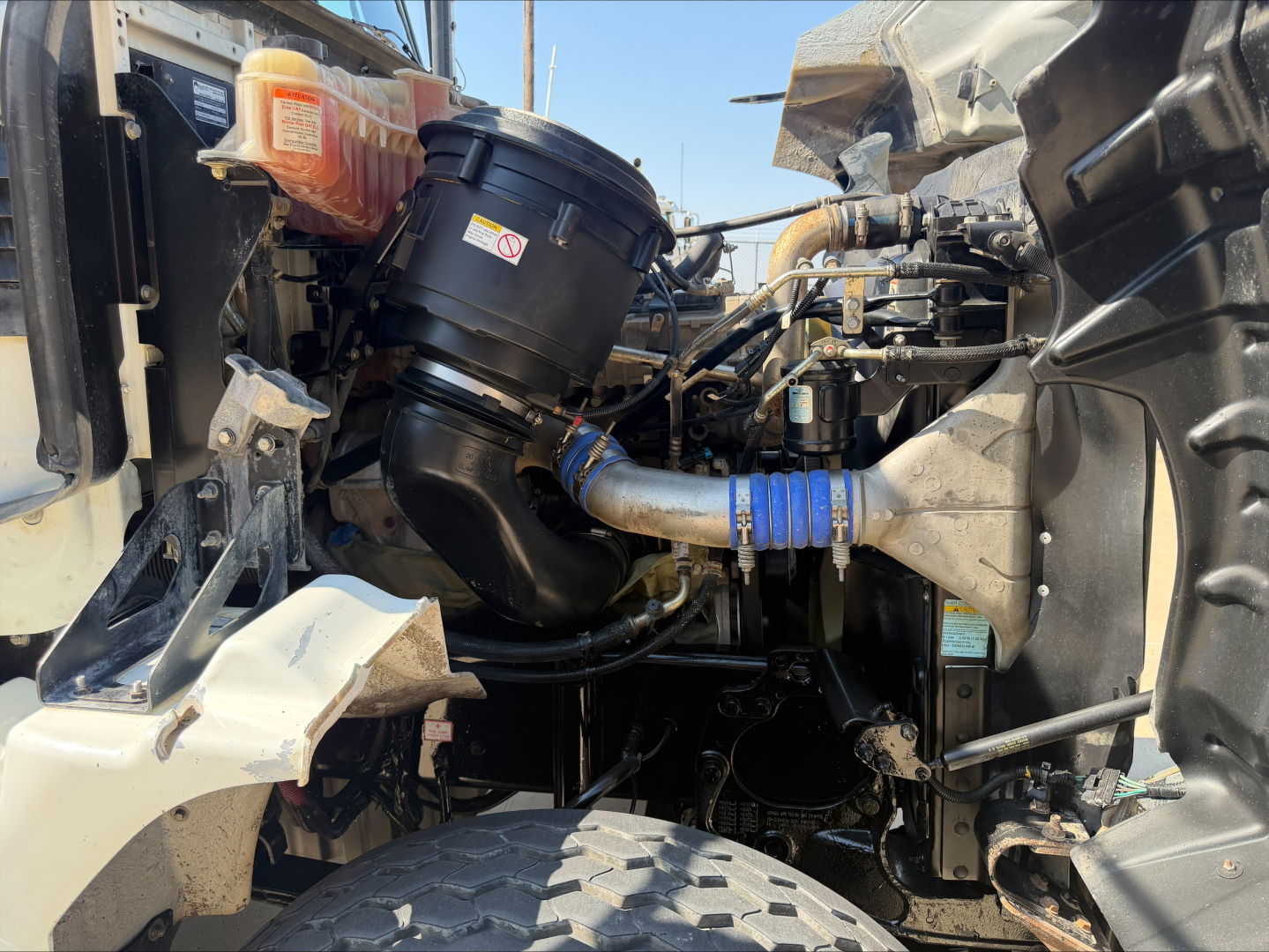 Engine bay of a 2017 Western Star 4700SF dump truck showing air filter housing, blue silicone hose, and surrounding engine components.