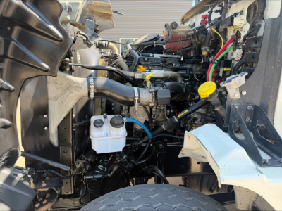 Western Star 4700SF engine bay showing coolant reservoir, various hoses, and engine components in a dump truck.