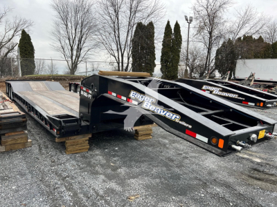 Lowboy trailer in a lot showing Eager Beaver branding and heavy-duty tilt-bed sections.