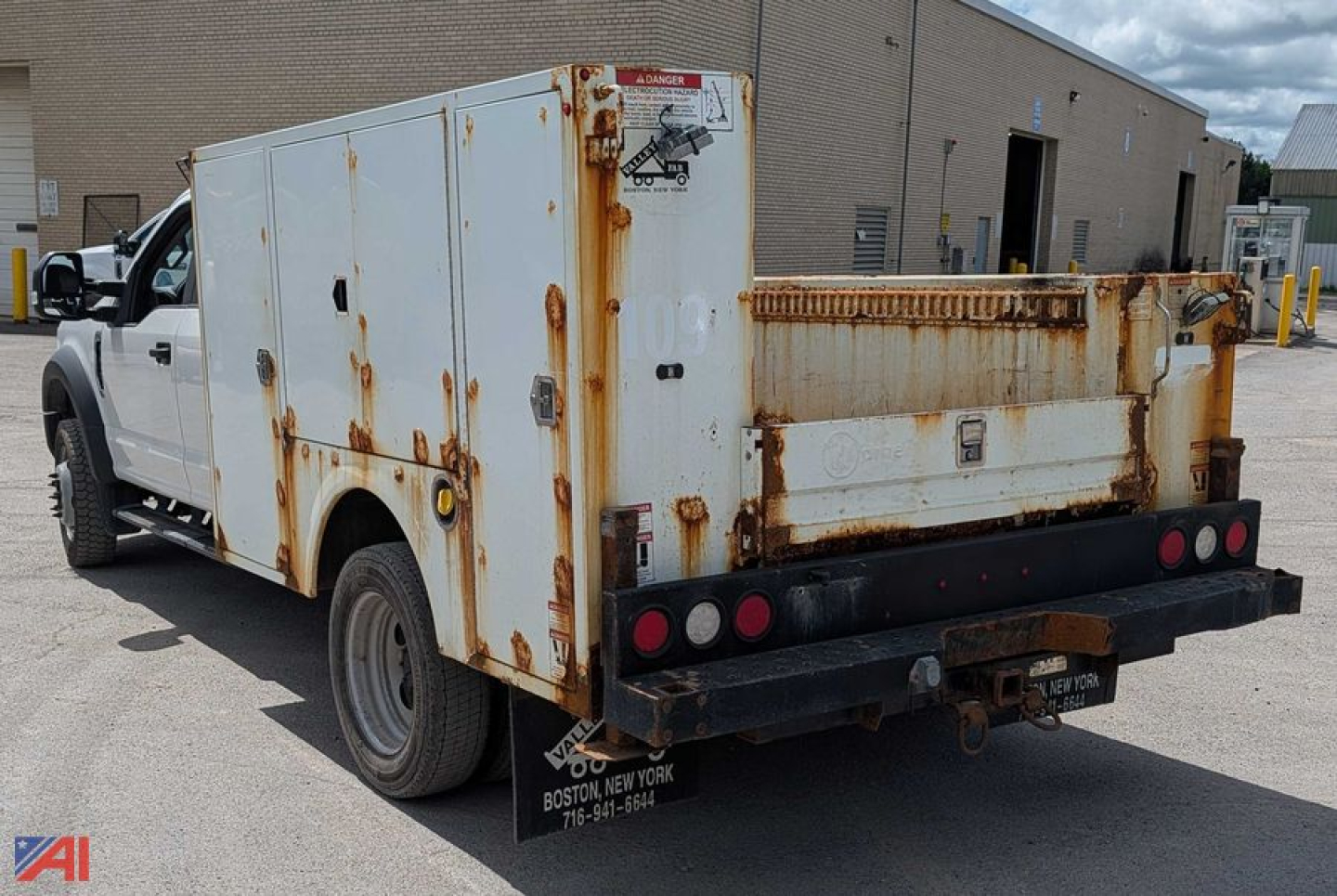 Service body utility truck rear and side view showing rusted white utility bed with storage compartments on a Ford F-450 Super Duty, dual rear wheels, service rear bumper, and warning labels.
