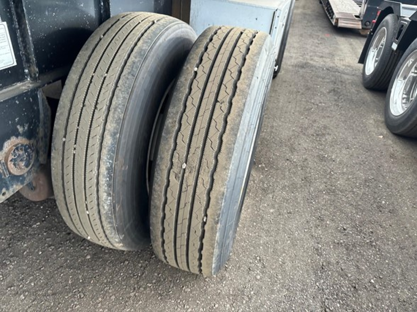 Twin rear tires of a Transcraft combo flatbed trailer showing tread patterns and sidewalls.