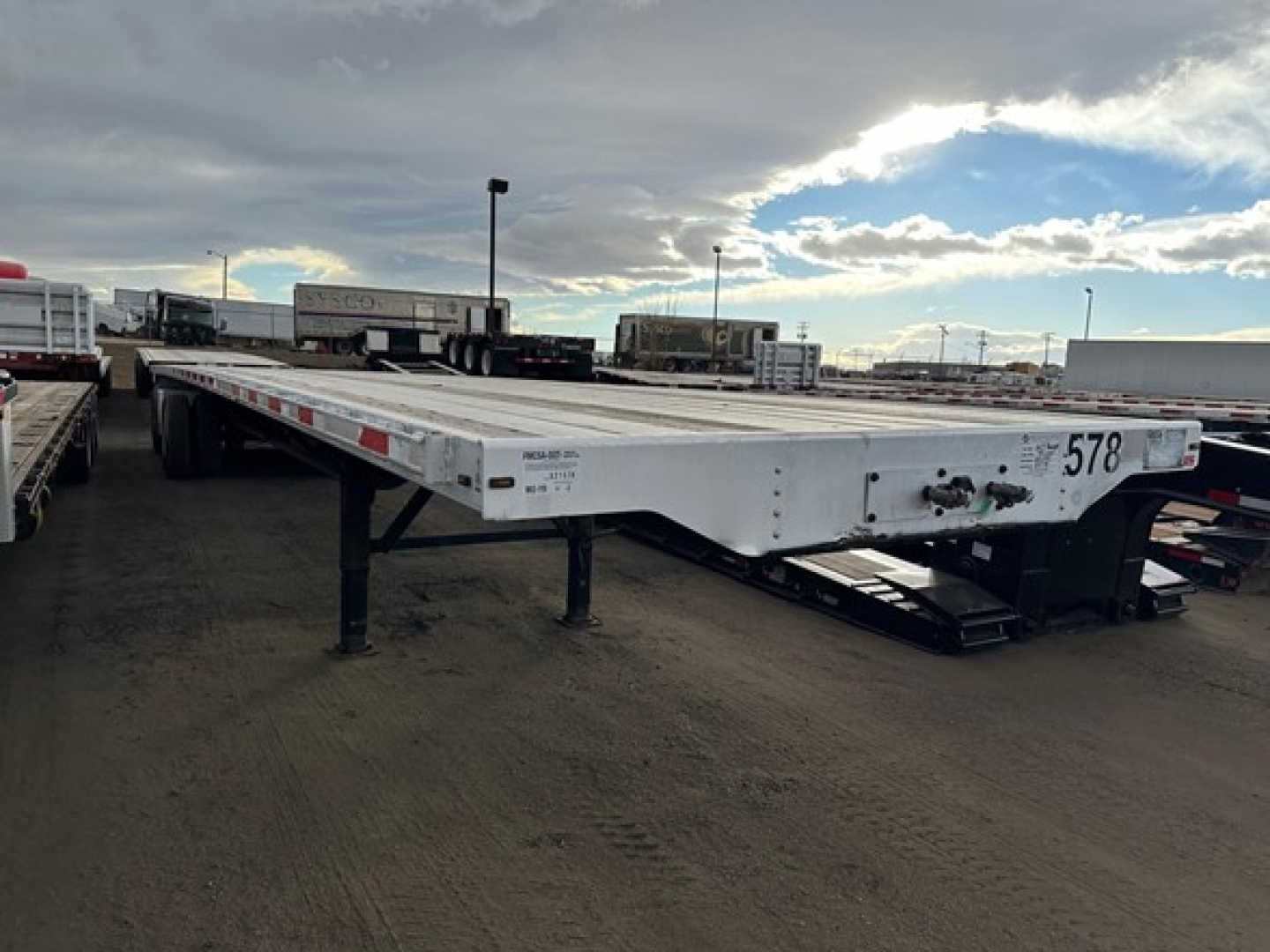 2017 Transcraft Combo Flatbed trailer side view showing white flatbed with black ramps and support legs.