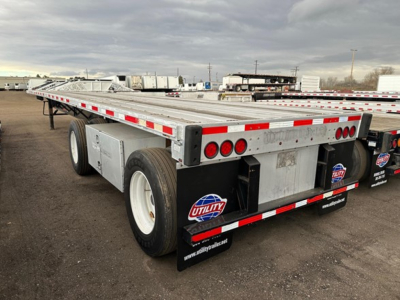Flatbed trailer rear and side view showing tandem wheels, reflective red and white strips, and Utility brand mud flaps.