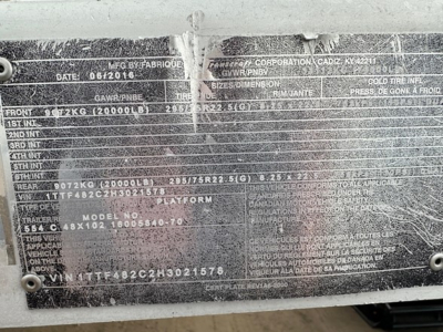 Plate with vehicle/trailer specs showing VIN and dimensional data, wear plate with stamped numbers, and various codes; difficult to read fully due to glare.